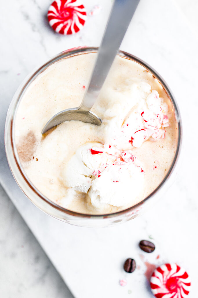 Overhead view of a glass of affogato topped with candy canes with a spoon digging into it