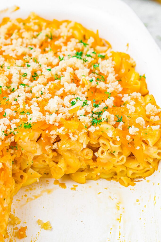 Close up shot of a tray of baked tofu mac and cheese with a slice taken out of it