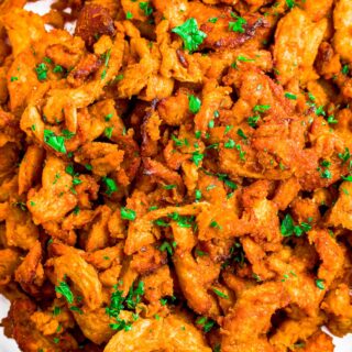 Close up overhead shot of bbq soy curls on a plate with minced parsley on top