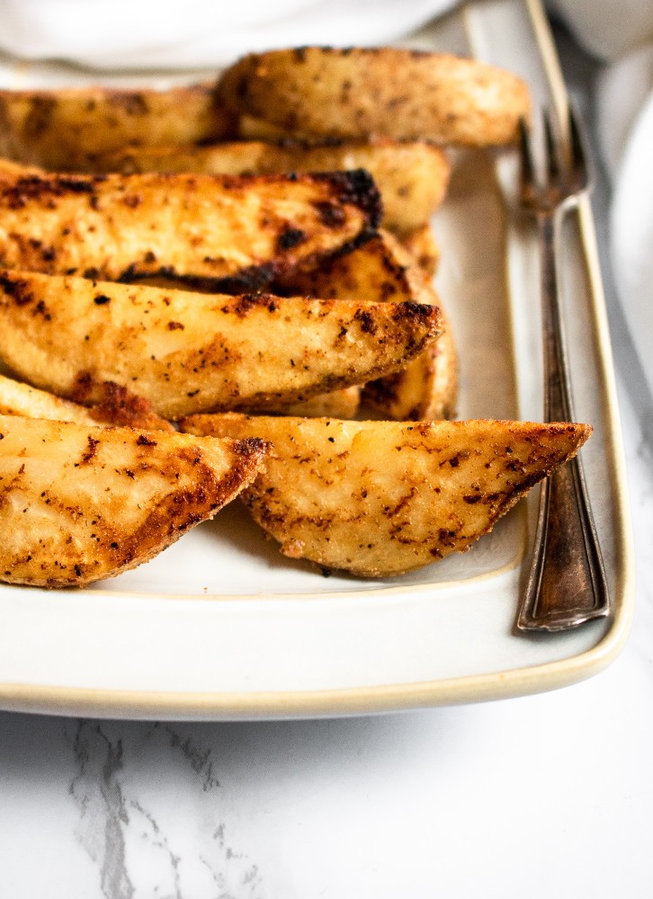 These cast iron potato wedges recipe is easy to make, super dependable, and can be altered to your specific spice/flavor desires. A healthier alternative to french fries, they’re great paired with ALL your summer grilling favorites or just as a snack served with ALL the dips! #vegan #potatoes #potatowedges #plantbased #castiron #comfortfood #veganrecipe