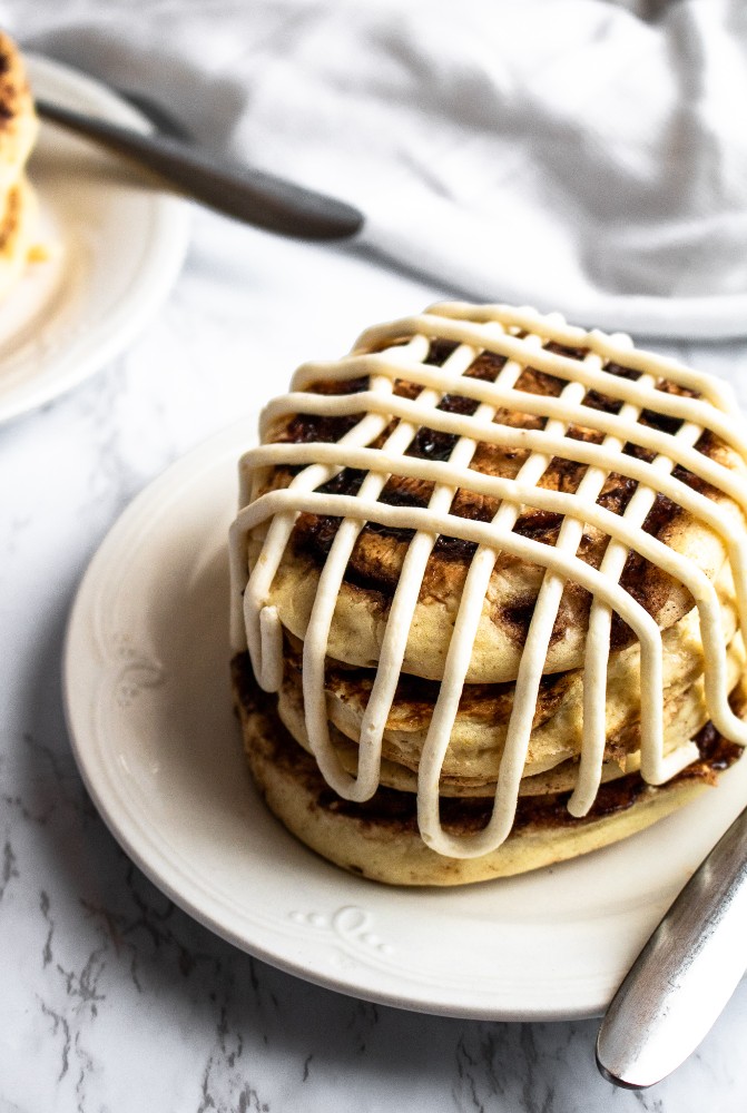 These vegan cinnamon roll pancakes are a deliciously indulgent dairy-free breakfast! They are fluffy pancakes with a coconut sugar + cinnamon swirl, topped with a decadent cream cheese frosting. #vegan #veganpancakes #cinnamonroll #cinnamon #veganbreakfast #pancakes #plantpowercouple #dairyfree // plantpowercouple.com