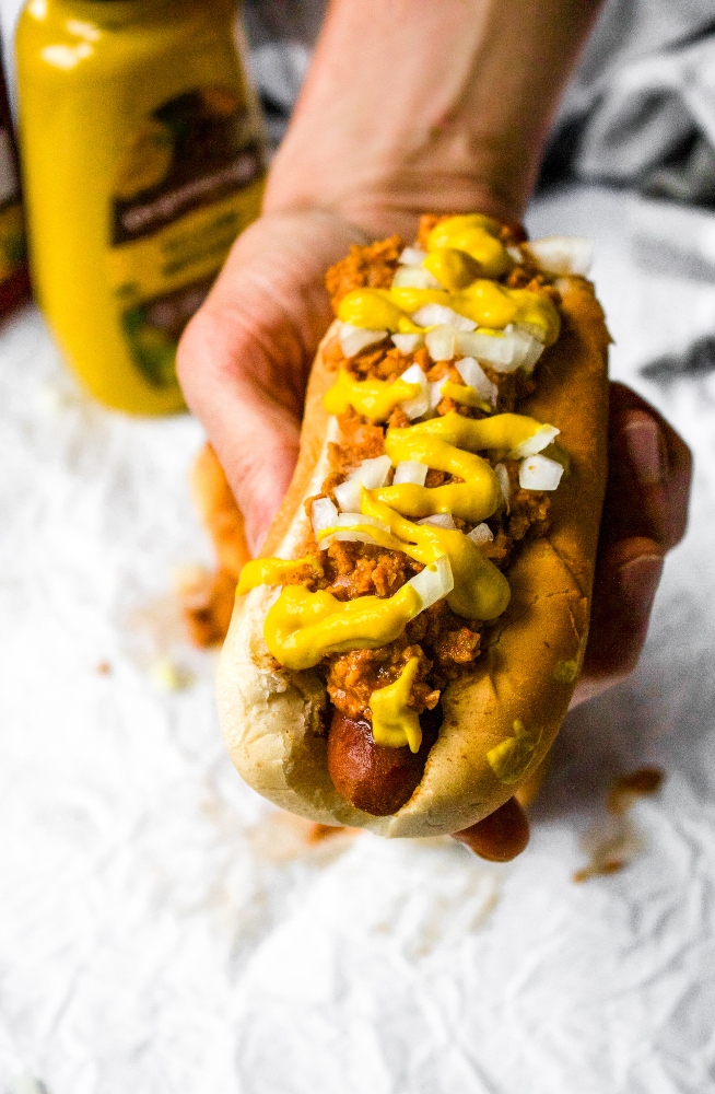 The Coney Dog is an American classic -- a hot dog topped with an all-meat mustard chili and diced onions. This vegan coney dog recipe is just as perfect for a weekend BBQ with friends as it is a weeknight family dinner at home with the kids. Easy and quick to make, you’ll love this vegetarian chili topping more and more with every delicious bite. This is not just a simple chili dog; this is a Coney Dog!