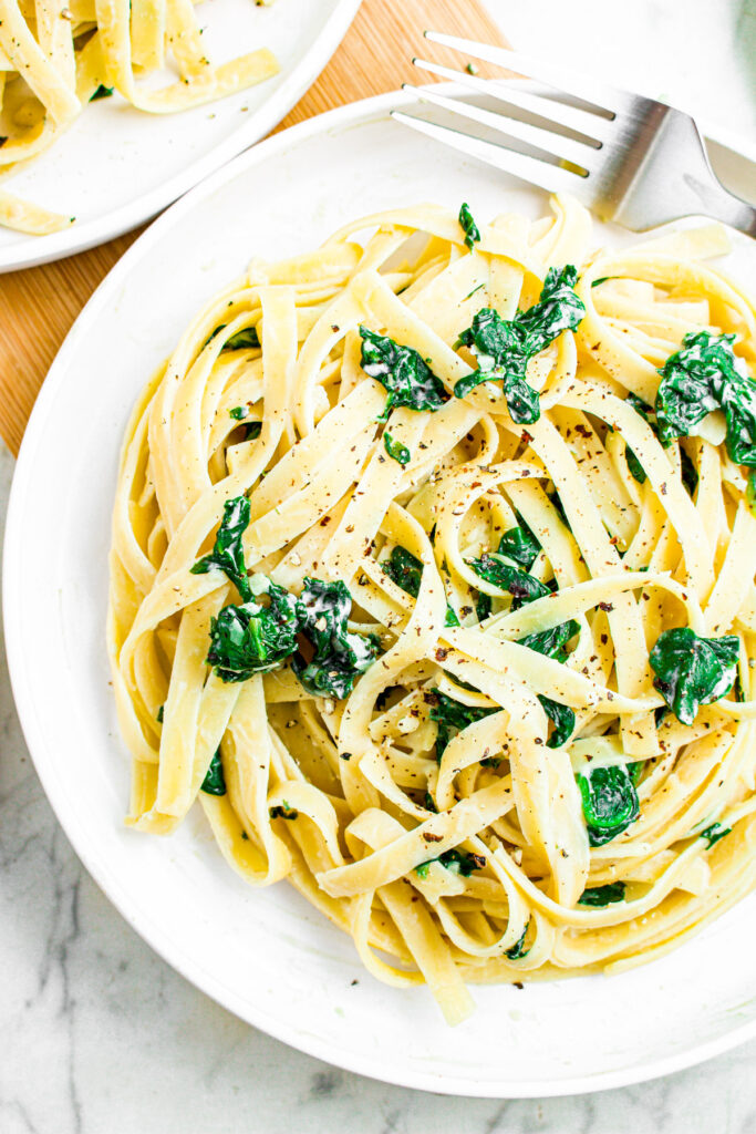 Overhead photo of a round white plate of creamy spinach fettuccine pasta