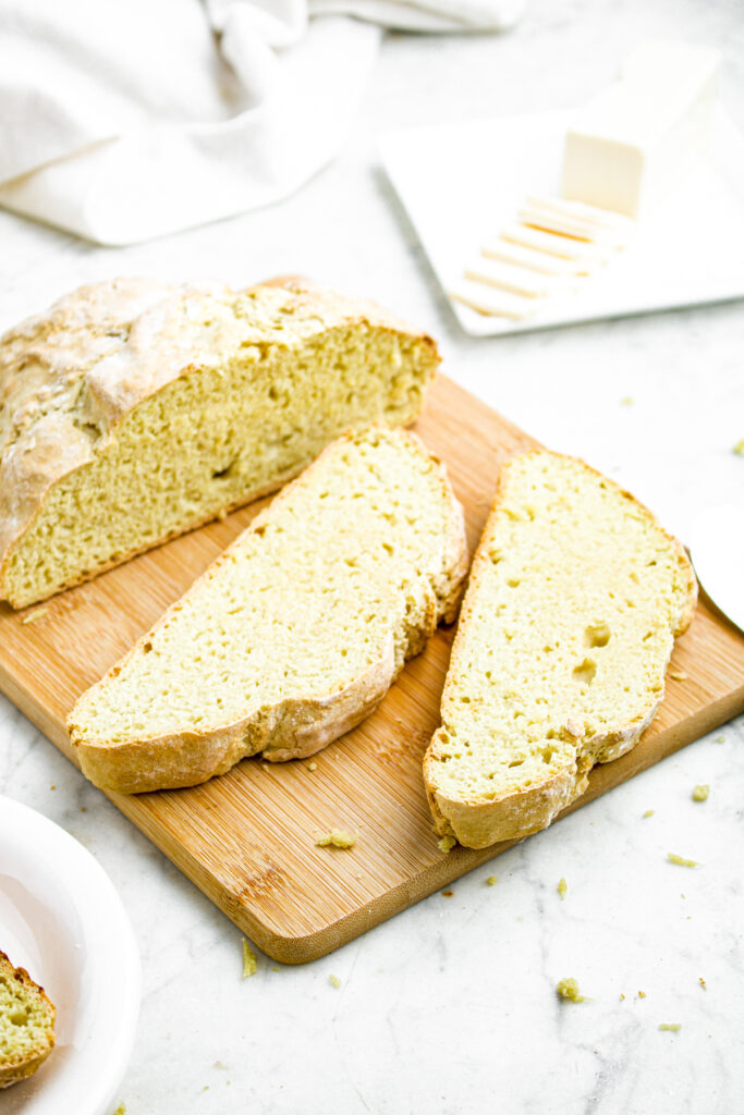 Overhead close up view of a partially sliced loaf of easy vegan bread on a wooden cutting board