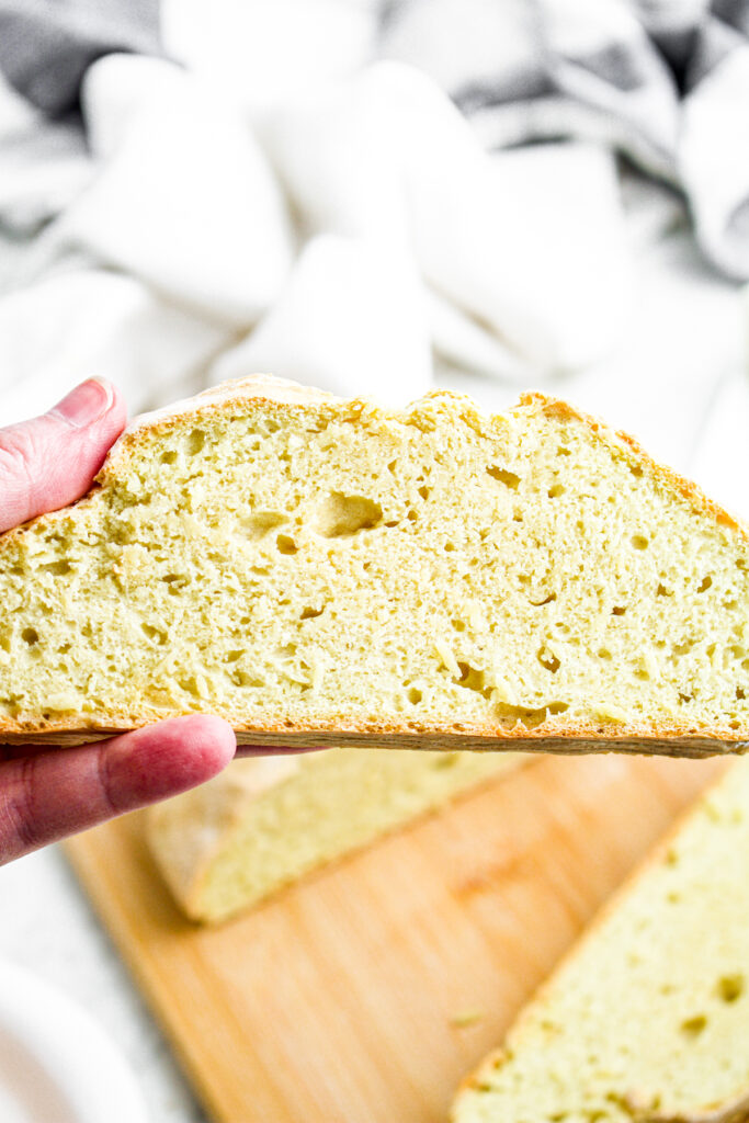 Head on view of a hand holding a slice of fresh homemade bread without yeast