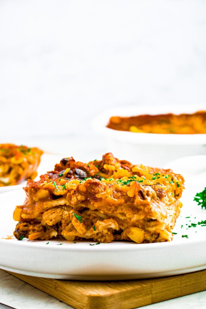 Head on photo of a slice of layered vegan enchilada pie on a round white plate.