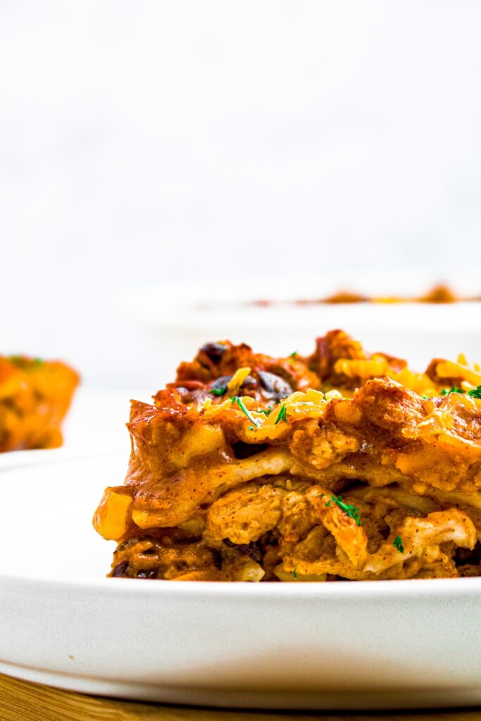 Close up photo of a slice of vegan enchilada casserole on a round white plate