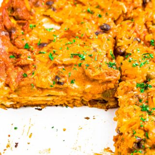 Close up head on photo of a meatless layered enchilada casserole in a large white casserole dish