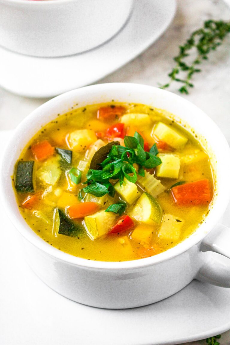 Overhead photo of a round white bowl of garden vegetable soup without tomatoes