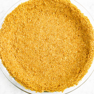Overhead zoomed in photo of a no-bake graham cracker crust in a clear glass pie dish