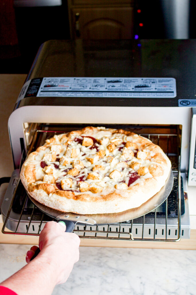 Overhead view of a pizza going into a pizza oven