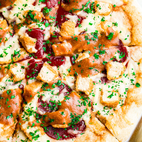 Close up overhead view of half a vegan Christmas pizza with mashed potatoes, cranberry sauce, and gravy