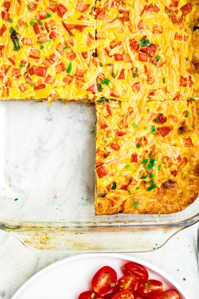 Overhead photo of a vegan breakfast casserole made with JUST egg in a casserole dish with the bottom left slice cut out of it