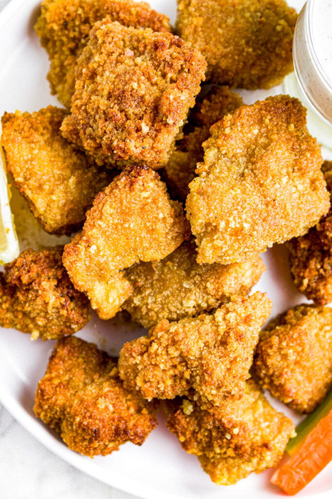 Overhead close up view of breaded tofu wings on a round white plate