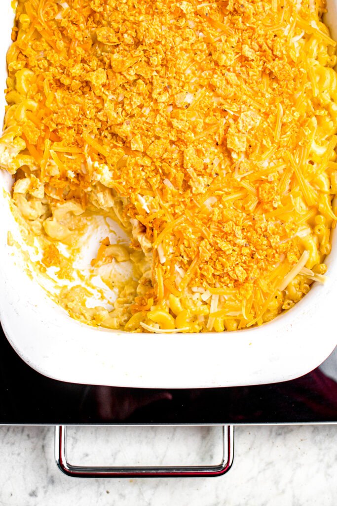 Overhead close up view of a rectangular white casserole dish of vegan baked macaroni and cheese sprinkled with Spicy Sweet Chili Doritos