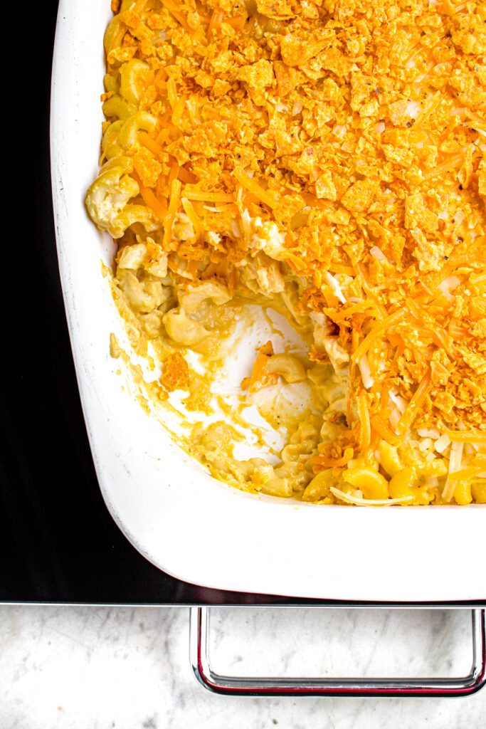 Overhead view of a rectangular white casserole dish of vegan baked mac and cheese sprinkled with Sweet Chili Doritos