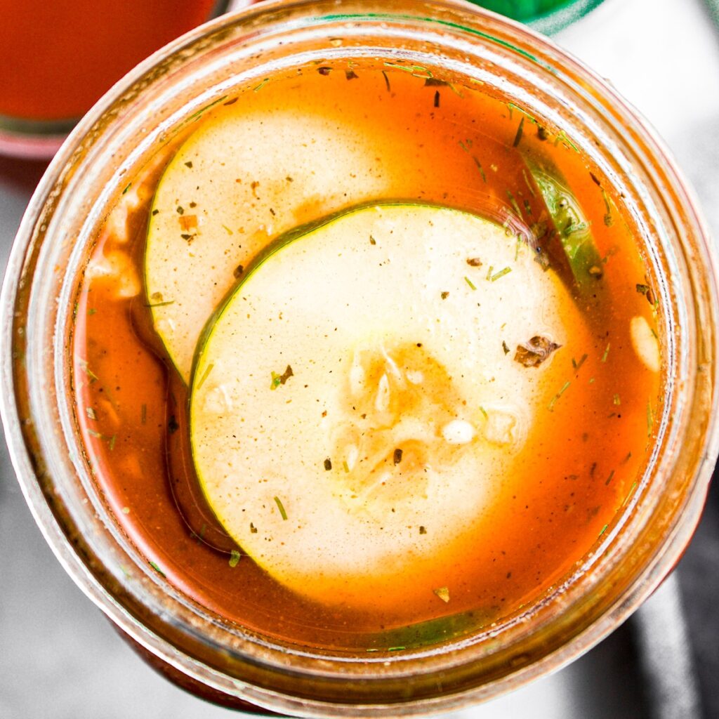 Overhead zoomed in view of a jar of spicy buffalo pickles in a homemade brine