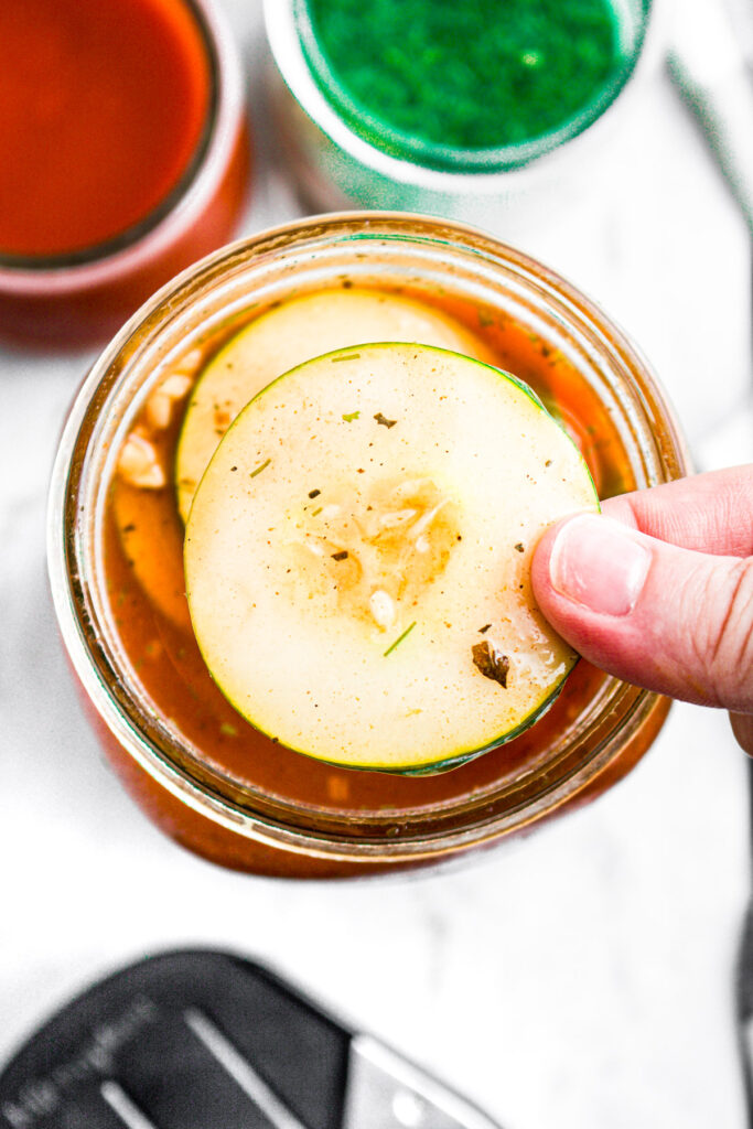 Overhead view of a hand lifting a pickle slice out of a jar