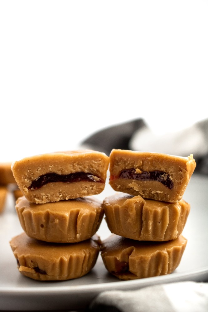 PB + J meets peanut butter cup in this killer combo of classic comfort foods! These delightful PB+J Cups are easy to make with only 4 ingredients, simple methods, and no heat required. They’re the ultimate summer sweet for your kids or the kid in us all! #vegan #dairyfree #vegancandy #veganrecipes #glutenfree //plantpowercouple.com