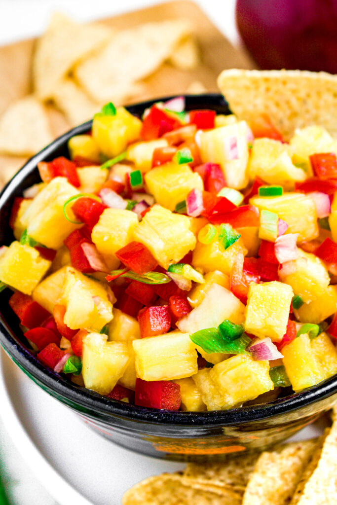 Overhead photo of a bowl of pineapple jalapeno salsa with a tortilla chip sticking out of it
