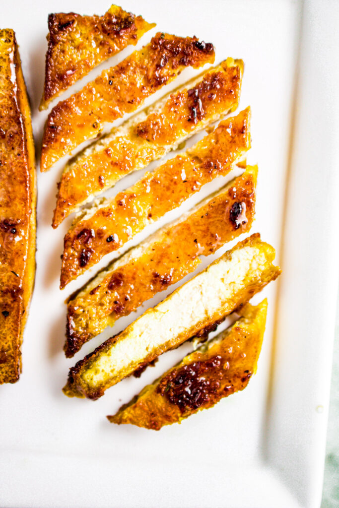 Close up overhead photo of a sliced pineapple glazed tofu cutlet on a plate