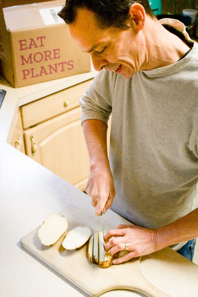 A man cutting potatoes while smiling