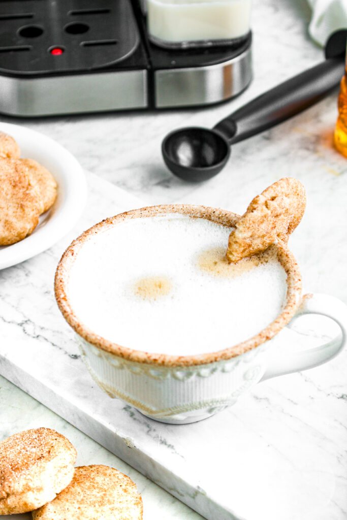Overhead view of a snickerdoodle latte with a pile of snickerdoodle cookies to the left