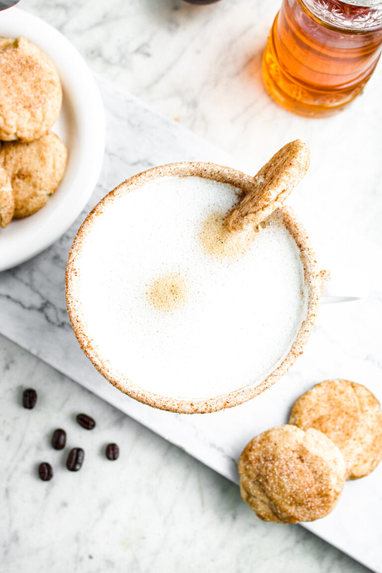 Overhead view of a cinnamon rimmed white mug filled with steamed oat milk