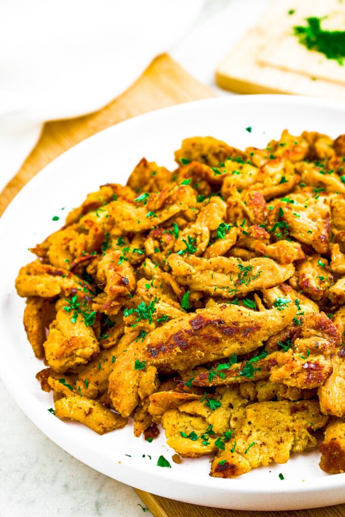 Overhead photo of half a round white plate with vegan chicken pieces on it