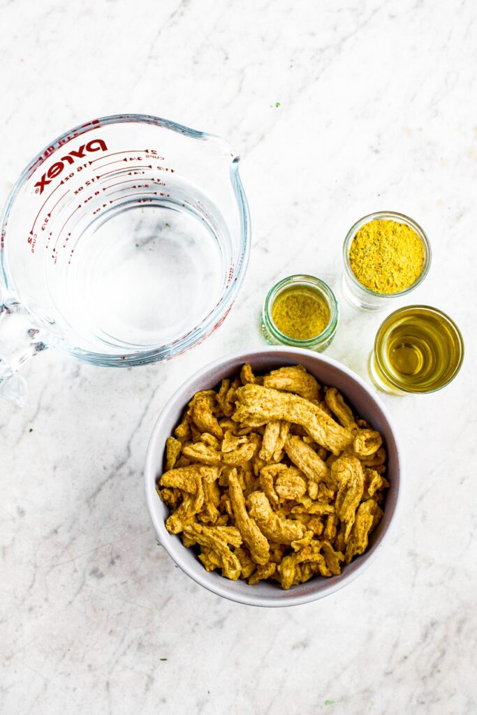 Overhead photo of the ingredients you need to make soy curl chicken: soy curls, water, olive oil, vegan bouillon powder