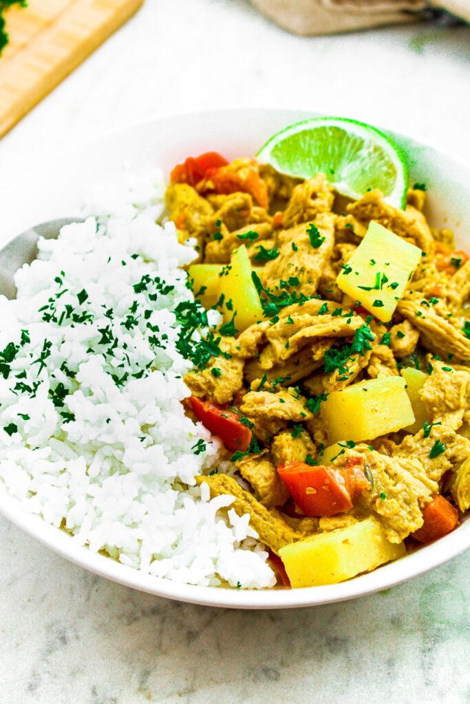 Close up overhead photo of a bowl of vegan soy curl curry with white rice sprinkled with minced green herbs