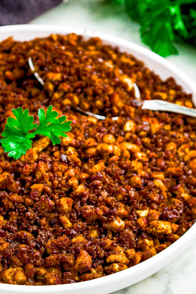 Overhead close up photo of tofu ground beef piled on a round white plate with a spoon digging into it