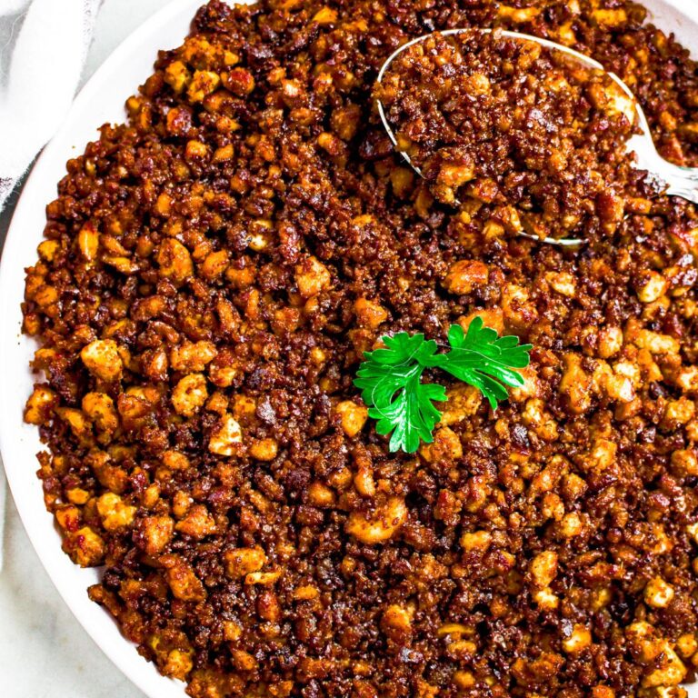 Overhead close up photo of a round white plate of tofu ground beef topped with a parsley leaf