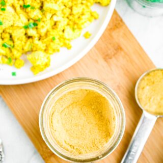 Overhead photo of an open mason jar with vegan egg seasoning in it. A plate of tofu scramble is in the top left corner.