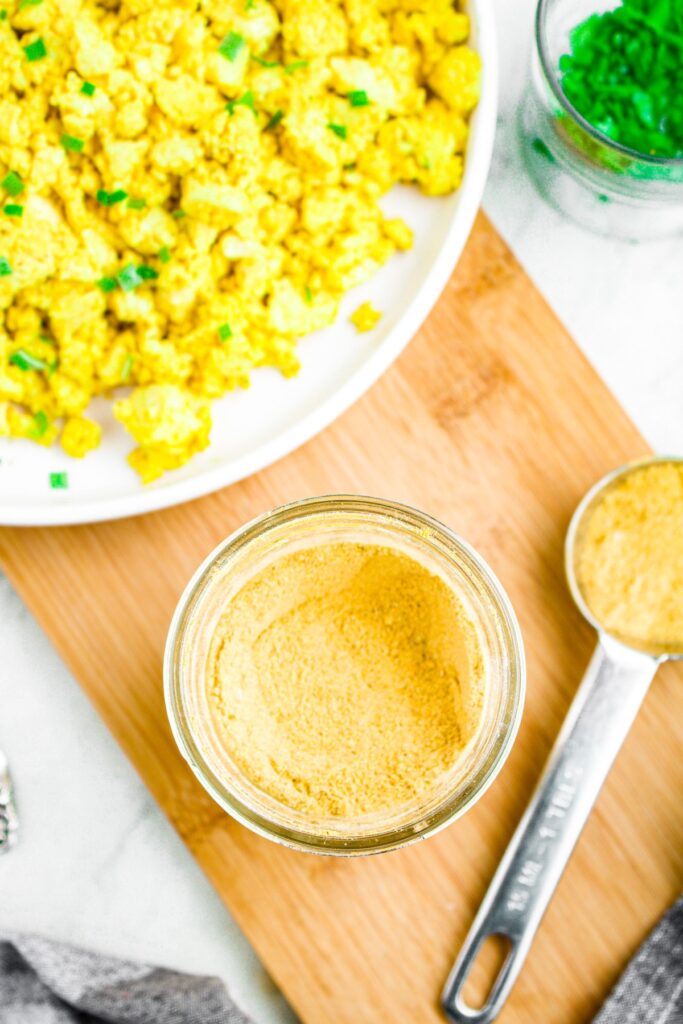 Overhead photo of an open mason jar with vegan egg seasoning in it. A plate of tofu scramble is in the top left corner.