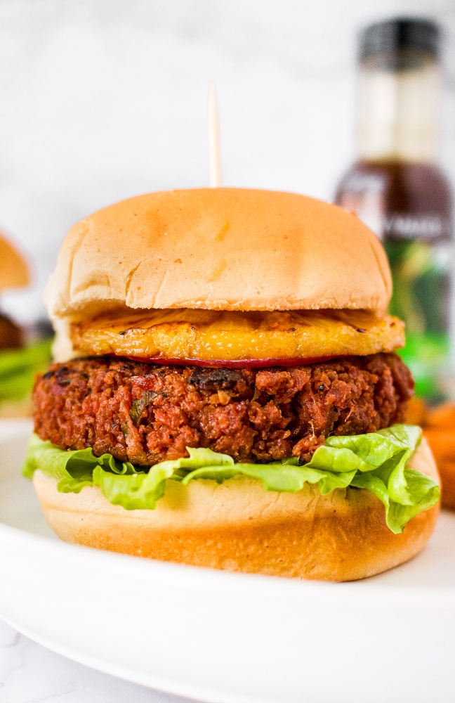 This Hawaiian-inspired vegan teriyaki burger is the meatiest and tastiest on the planet! If you love teriyaki chicken, you’re going to love this plant-based homemade burger! It starts with a blend of TVP and vital wheat gluten with a little beet puree thrown in for a meaty color. Then, it’s flavored with the perfect blend of garlic, ginger, red onion, and teriyaki sauce. It’s topped with a grilled pineapple slice and spicy teriyaki mayo. It’s a great vegetarian option for cookouts and guaranteed to be your new favorite summer veggie burger.