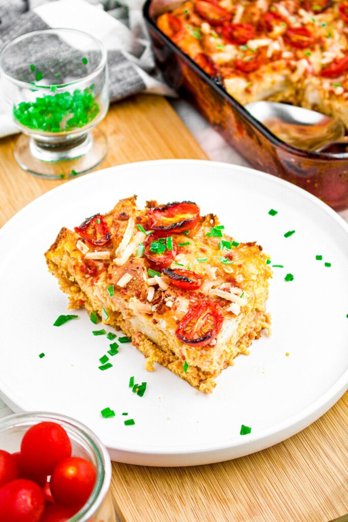 Overhead photo of a slice of vegan overnight breakfast casserole sprinkled with fresh green herbs on top