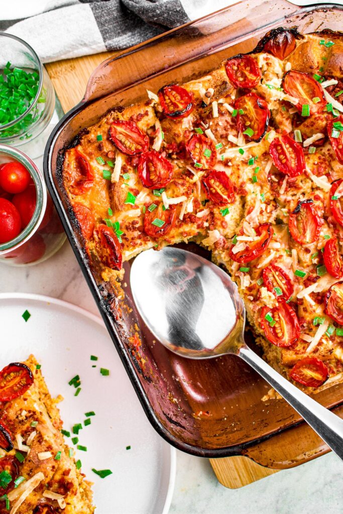 Overhead photo of a baking dish of vegan overnight breakfast casserole with a piece taken out and a spoon sitting in it