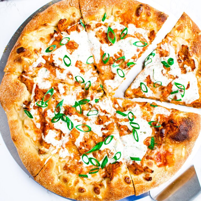 Overhead view of a vegan buffalo chicken pizza with one slice pulled out