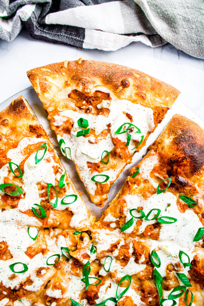 Overhead close up view of a slice of vegan buffalo pizza with one slice pulled out