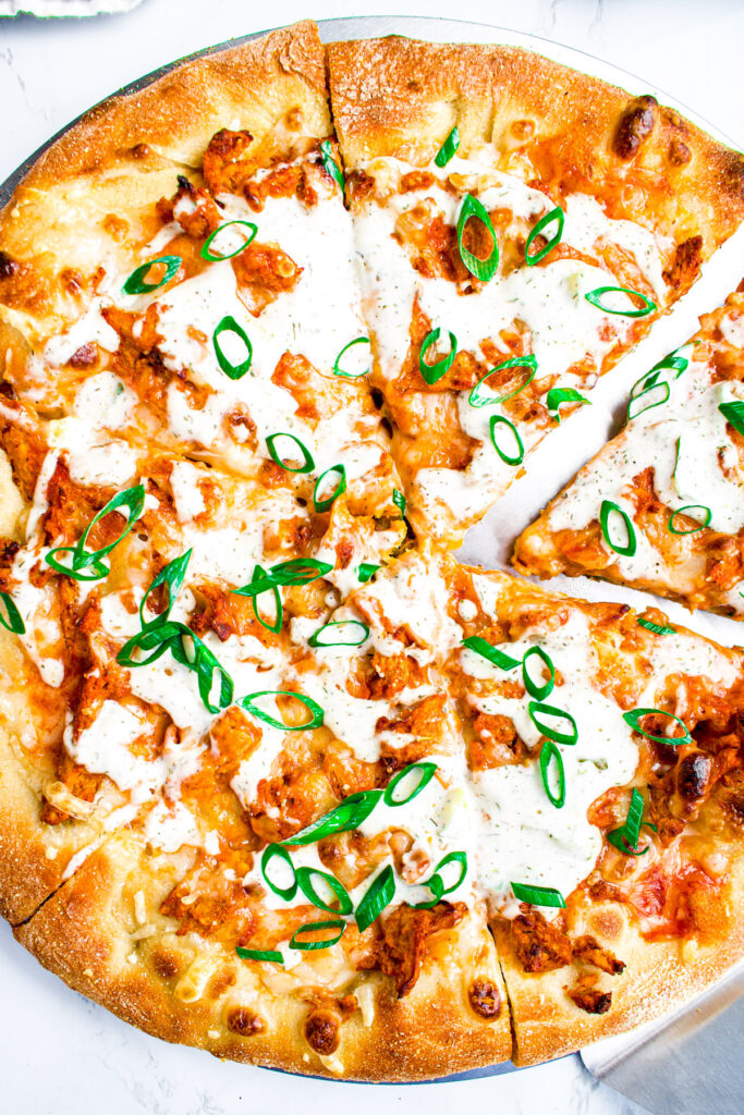 Overhead view of a buffalo soy curl pizza topped with sliced green onions