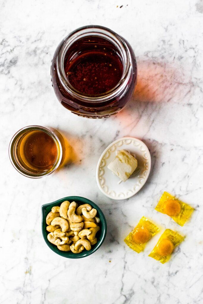 Overhead shot of all the ingredients you need to make dairy free butterbeer: cream soda, vegan butter, cashews, butterscotch candies.