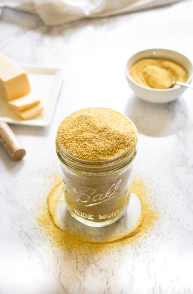 This easy 6-ingredient vegan cheese seasoning is a staple in our kitchen! Use it as a dairy-free parmesan on pasta, a cheesy popcorn seasoning, and mix it with vegan butter to make the BEST dairy-free garlic bread. It can also be used to make an easy cheesy pasta sauce! #vegan #vegancheese #veganseasoning #dairyfree #plantbased #nutritionalyeast #veganpopcorn
