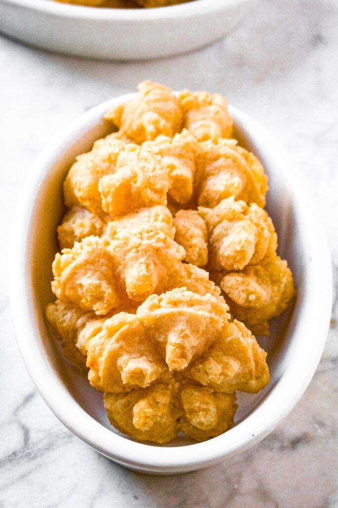 Head on shot of dairy free cheese straws arranged in an oval shaped white dish.