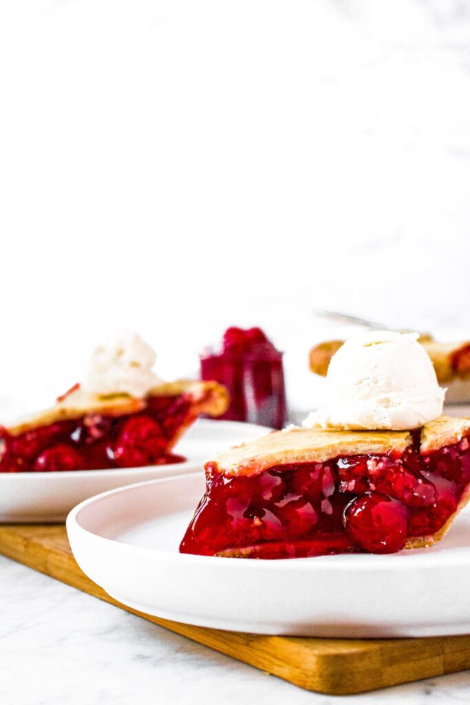 Head on photo of two slices of vegan cherry pie on individual round white plates