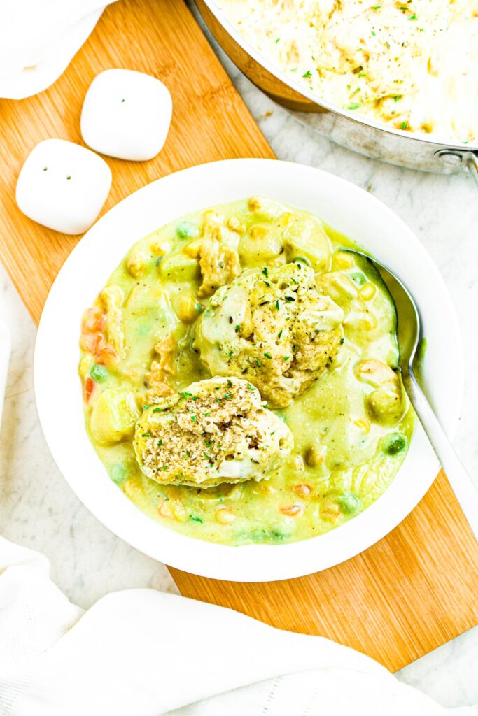 Overhead photo of a round white bowl with creamy vegan stew and two dumplings on top