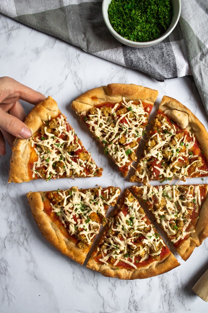 Vegan Chicken Parm Pizza is a fun dinner recipe that’s kid-approved, freezer-friendly, and easy to make. A delicious twist on two classic comfort foods, you can make this vegan pizza from-scratch OR use some of the store-bought shortcuts we suggest. #vegan #plantbased #veganpizza #pizzarecipe #vegancomfortfood #comfortfood #pizza #dinner