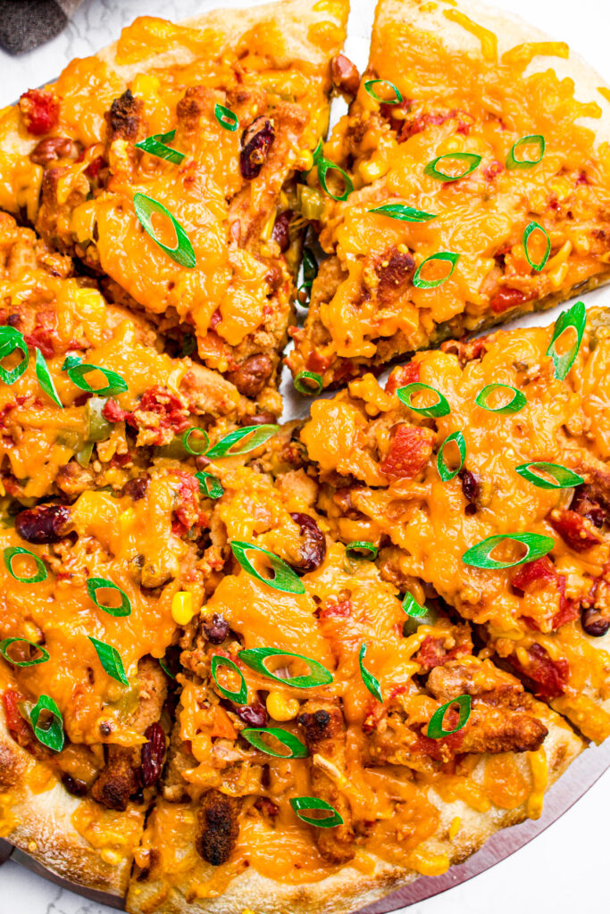 Overhead zoomed in view of a vegan chili cheese pizza with sliced green onions