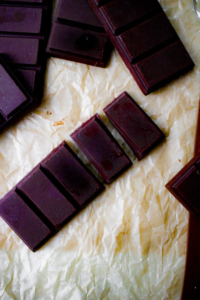 Close up overhead shot of a pile of chocolate bars. One chocolate bar is pulled away from the rest and some of the rectangles are broken off
