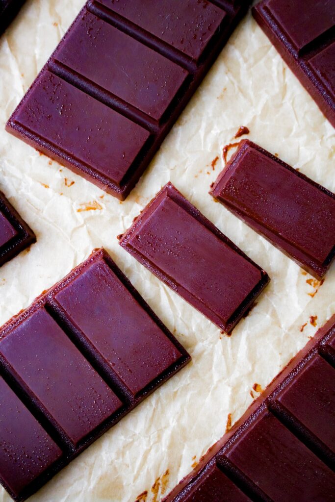 Overhead close up shot of a broken up homemade chocolate bar on parchment paper